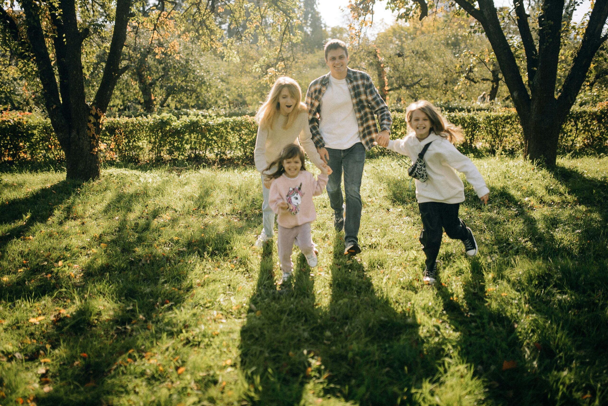 A joyful family with two kids playing in a sunlit countryside setting, enjoying a summer day.